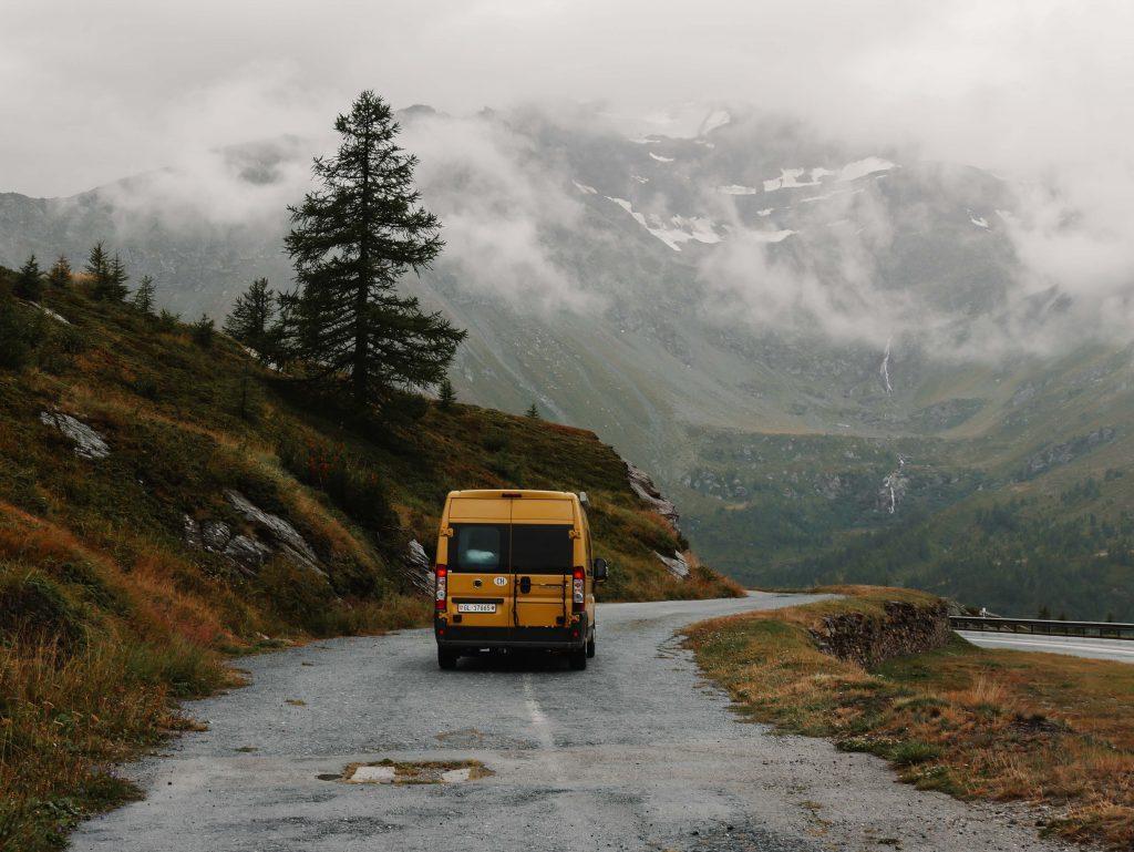 Camping Norditalien, gelber Camper auf dem Pass in regnerischer Landschaft