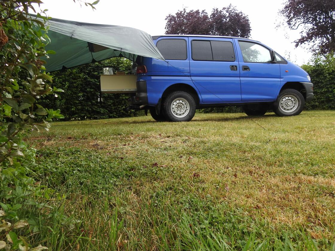 Bild von einem zum Camper ausgebauten Minivan auf der Wiese.