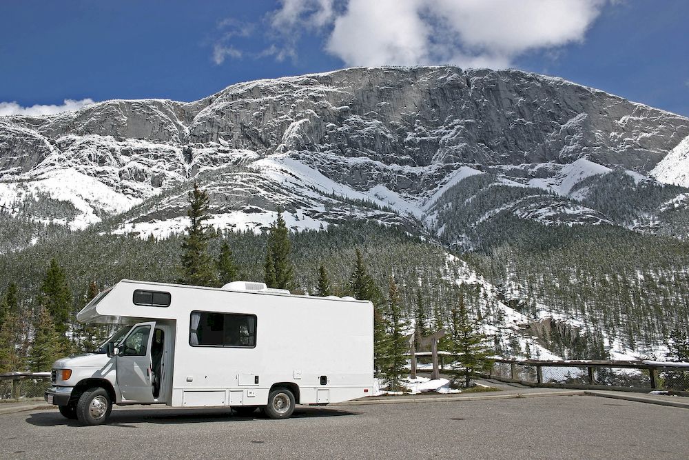 An American motorhome in front of snow covered mountains.
