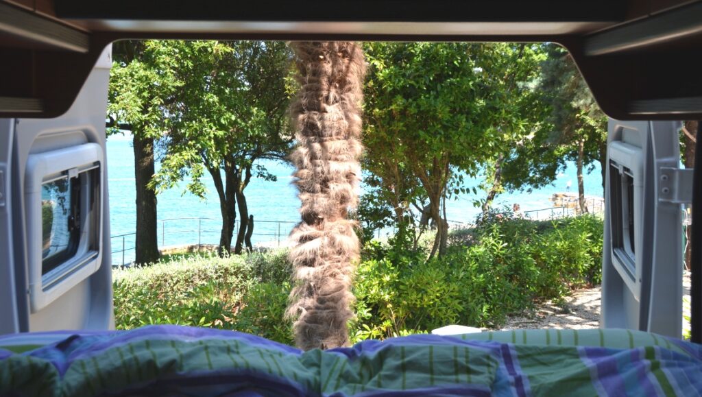 View to nature and sea, from the open back doors of a campervan