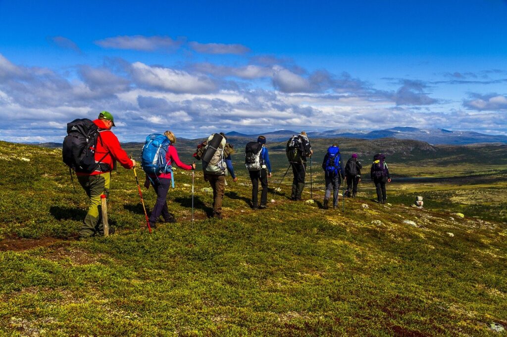 En grupp vandrare med packning vandrar i ett öppet landskap