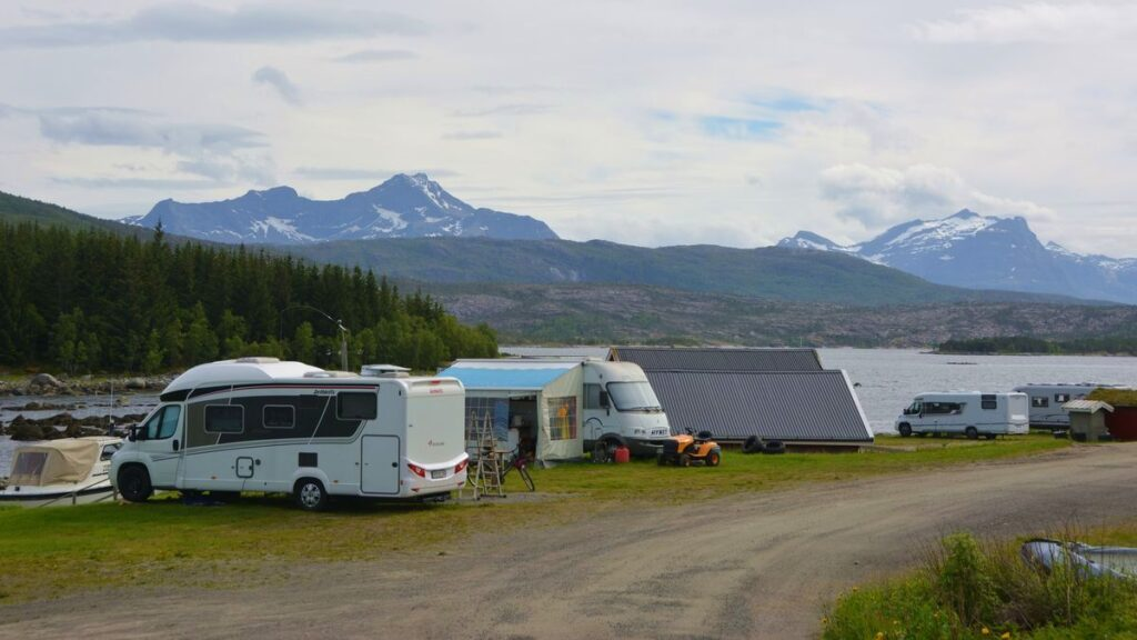 Véhicules de camping sur un terrain de camping, avec des montagnes en arrière-plan.